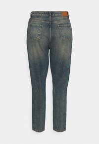 Niebieskie dżinsy o lekko wyblakłym wykończeniu. Prosta nogawka z dwoma tylnymi kieszeniami i skórzaną metką w kolorze brązowym na pasku.