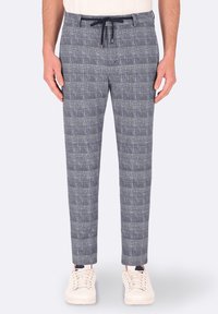 Pantaloni grigi a fantasia con una finitura testurizzata, dotati di vita con cordoncino e vestibilità slim, abbinati a sneakers bianche.