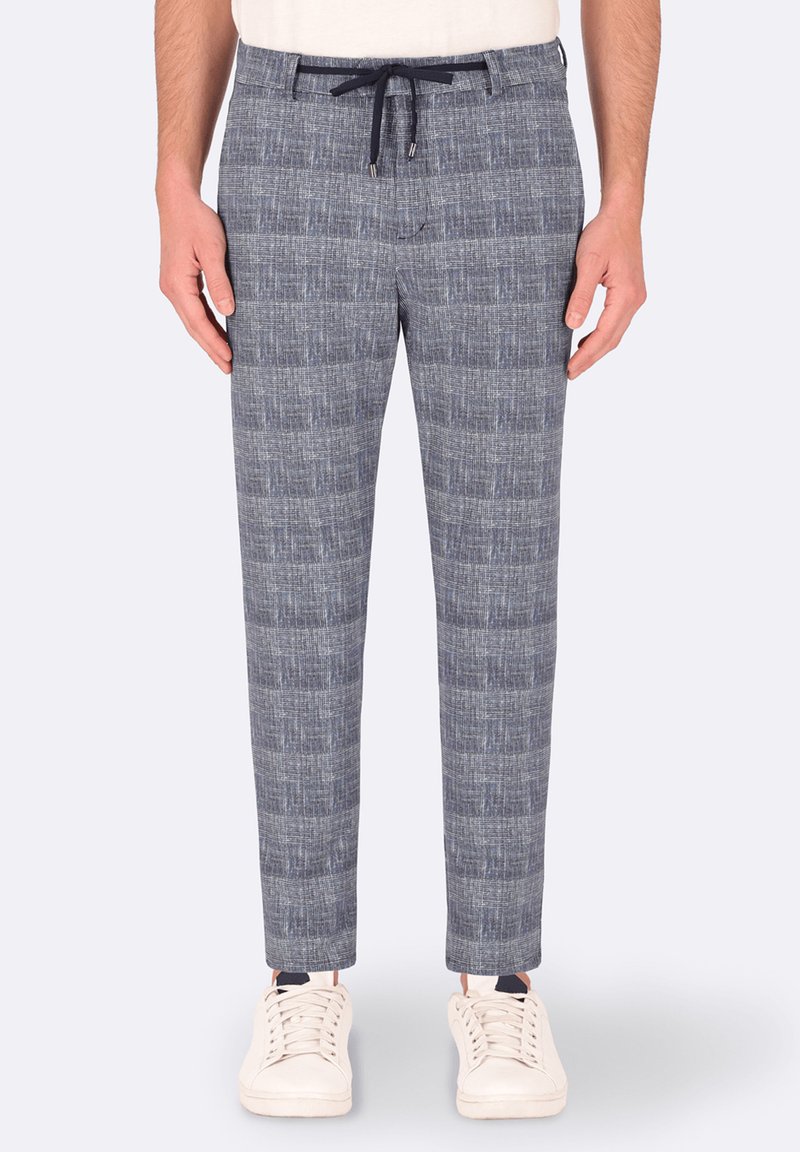 Pantaloni grigi a fantasia con una finitura testurizzata, dotati di vita con cordoncino e vestibilità slim, abbinati a sneakers bianche.