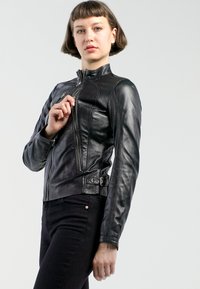 Schwarze Lederjacke mit taillierter Passform, hohem Kragen und diagonalem Reißverschluss. Verfügt über silberne Hardware und einen Gurtakzent in der Taille.