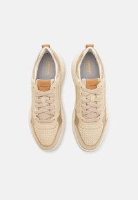 Sneakers beige con una toma in pelle liscia e dettagli in tessuto, caratterizzati da perforazioni, lacci piatti e una suola ammortizzata. Logo Geox visibile.