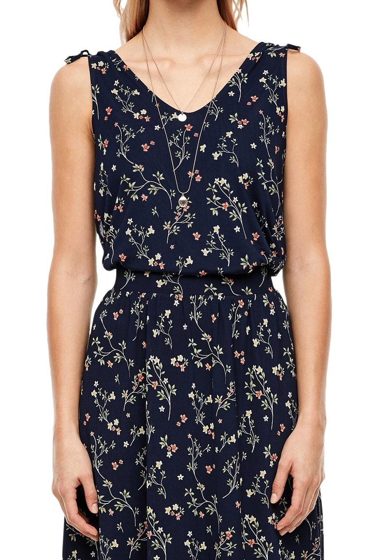 Robe sans manches bleu marine avec petit imprimé floral blanc et orange, col en V, taille élastique et colliers pendentifs superposés.