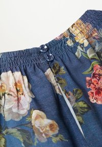 Tkanina s květinovým vzorem v tmavě modré barvě, se elastickým pasem a dvěma kulatými námořnickými knoflíky. Hladký povrch s barevnými květinovými motivy.