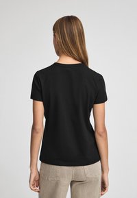 Svart bomulls-T-shirt med korta ärmar och rund halsringning, med en slät yta och en figurnära passform, sett bakifrån.