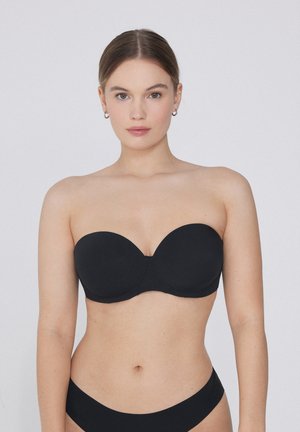 Zwarte strapless beha met naadloze cups, gemodelleerde vorm en gladde textuur. Ontworpen voor een onopvallende pasvorm, met een minimalistische stijl.