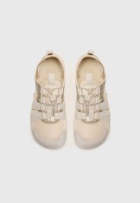Light beige athletic shoes with mesh upper, elastic straps, and rubber soles. Features pull tab and textured rubber toe cap.
