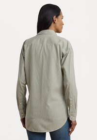 Csíkos gombos ing világoszöld és fehér színben, hosszú ujjal, hegyes gallérral és ívelt aljjal. Finom, könnyű anyagból készült.