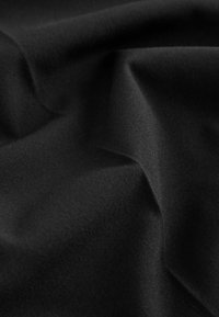 Must mustriga kangas, millel on sile tekstuur, pehmed voldid ja peened kortsud. Ühtlane värv, ilma nähtavate mustrite või kaunistusteta.