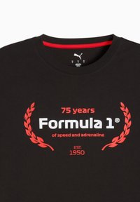 Sort bomulds t-shirt med rød accent på halsudskæringen, grafisk tryk: "75 år Formel 1" omkranset af laurbærblade, etableret 1950.