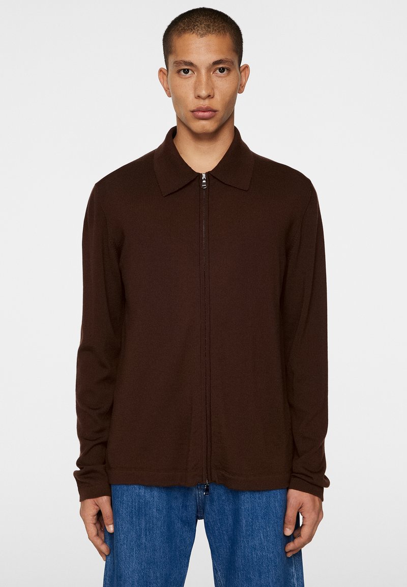 Giacca marrone a maniche lunghe con colletto e zip frontale. Realizzata in tessuto testurizzato, presenta una linea dritta e un design minimalista.