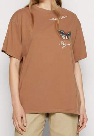 Ruskea puuvillainen t-paita lyhyillä hihoilla, jossa on tekstit "Ahead of Time" ja "Pegasus" sekä brodeerattu perhonen.