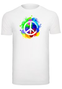 Hvid t-shirt med et farverigt splatter-design, som har et centralt fredssymbol i hvidt omrids, omringet af livlige farver.