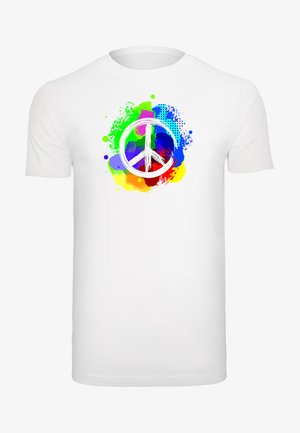 T-shirt en coton blanc avec un graphique coloré du symbole de la paix entouré d'éclaboussures de vert, bleu et orange ; associée à un jean bleu clair.