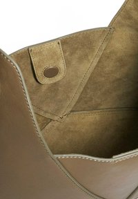 Olive green suede tote bag interior with a soft texture, featuring a snap closure and beige stitching along the edges.