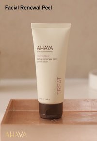 Tubetto di Peeling Rinnovatore per il Viso in crema chiara con tappo marrone scuro. L'etichetta presenta "AHAVA", "TIME TO TREAT" e "TREAT" in testo viola. Dimensione da 100ml.