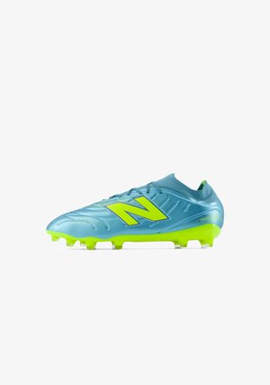 Blå og neongrøn fodboldstøvle med stort neongult New Balance-logo og knotter på sålen til spil på fast underlag.