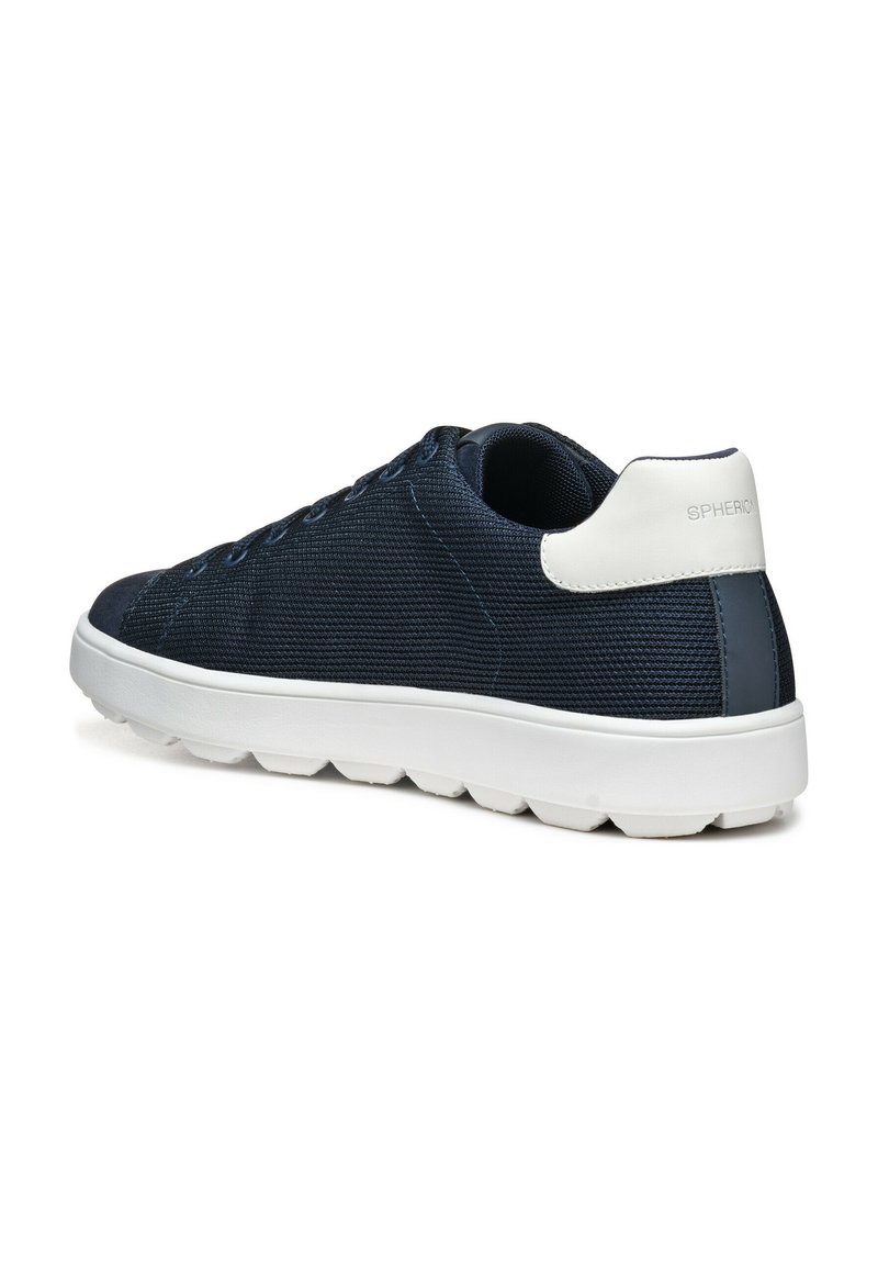 Baskets bleu marine avec une tige en maille texturée, accent blanc au talon et une épaisse semelle blanche présentant un motif en zigzag pour l'adhérence.