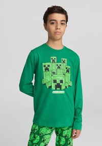 Camicia verde a maniche lunghe con grafica del Creeper di Minecraft, abbinata a pantaloni da pigiama verdi con un motivo a ripetizione del Creeper.