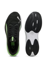 Zapatillas deportivas negras con acentos verdes, parte superior de malla, suela plana de goma negra y un diseño de cordones distintivo. Presenta el logo de Puma.