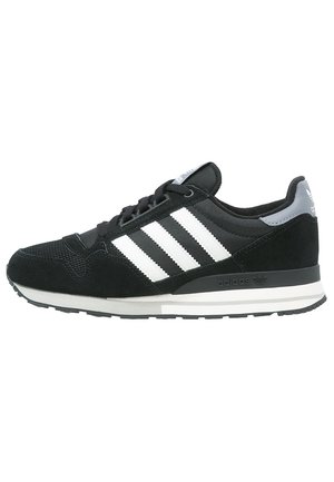 Sort Adidas sneaker med hvide striber, gråt hælstykke, sort sål og snørelukning, vist fra venstre side.