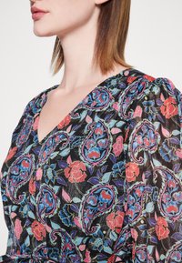 Robe en tissu noir avec des motifs floraux paisley dans des teintes vives de rouge, bleu et vert ; dotée d'un décolleté en V et de manches ballons.