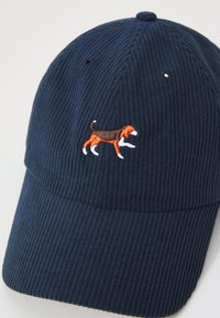Marine corduroy baseballcap met verhoogde borduursel van een bruine en oranje hond die wandelt. Voorzien van een gebogen rand en ventilatie-oogjes.
