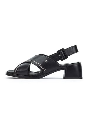 Sandalia negra de cuero tipo slingback con un bajo tacón bloque, diseño recortado, costuras en contraste y correa ajustable en el tobillo.