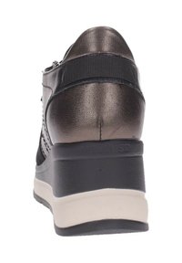 Zapatilla cuña negra y metálica con parte superior texturizada, detalle de cremallera y suela crema en contraste. Diseño ergonómico para mayor comodidad.