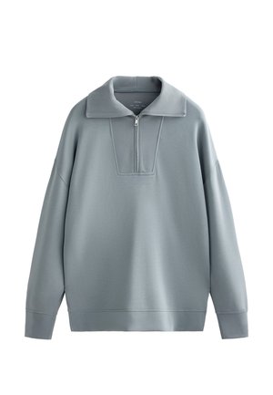Pullover grigio chiaro con collo a mezza zip, maniche ampie e un pannello alare strutturato. Realizzato in un tessuto morbido e liscio con vestibilità rilassata.