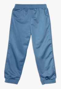 Pantaloni sportivi azzurri realizzati in materiale sintetico liscio. Presentano una vita e polsini elasticizzati per una vestibilità comoda. Nessun motivo visibile.
