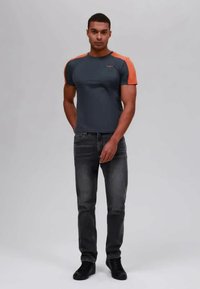 Gray short-sleeve shirt with orange accents, slim fit, paired with dark jeans and black shoes. Smooth fabric texture. Clean design.