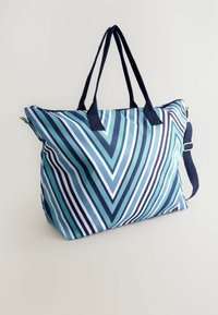 Geantă mare tip tote cu un model geometric alb și albastru în dungi. Dispune de mânere marini închise și o curea de umăr ajustabilă.