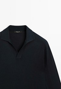 Tmavě modrá polo košile s výstřihem do V, vyrobená z měkké bavlněné tkaniny. Má minimální design a žádné viditelné vzory nebo akcenty.