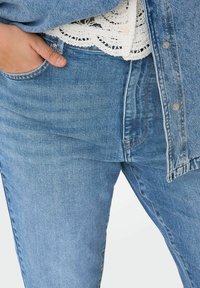 Jeans en denim bleu clair à coupe ajustée, avec un style classique à cinq poches, un léger délavage et des détails cousus sur les poches.
