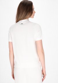 Top a maniche corte, di colore rosa chiaro, con scollatura rotonda e rifiniture a costine. Tessuto morbido con una vestibilità leggermente oversize, presenta un piccolo logo sul retro.