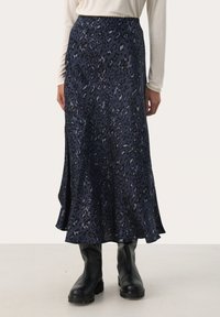 Marineblaues Tiermotiv-Midikleid aus glattem Stoff, mit weitem Saum und elastischem Bund. Kombiniert mit schwarzen kniehohen Stiefeln.