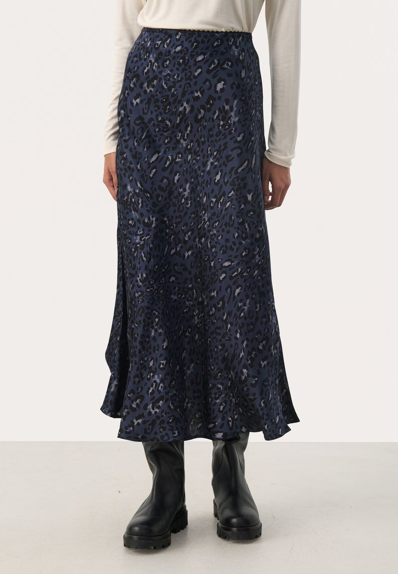 Marineblaues Tiermotiv-Midikleid aus glattem Stoff, mit weitem Saum und elastischem Bund. Kombiniert mit schwarzen kniehohen Stiefeln.