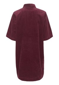 Bordeauxrotes Cordhemd mit kurzen Ärmeln und Kragen, das eine strukturierte, gerippte Oberfläche und eine lockere, weit geschnittene Passform aufweist.