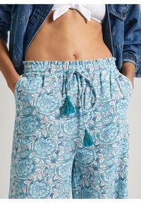 Světle modré kalhoty s květinovým vzorem, elastickým páskem, třásňovými detaily a bočními kapsami, vyrobené z měkkého a prodyšného materiálu.