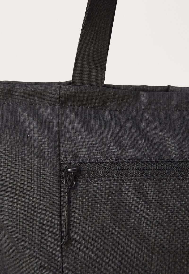 Bolso tote negro hecho de tela texturizada, con una abertura superior y un pequeño bolsillo con cremallera en el lateral para un almacenamiento seguro.