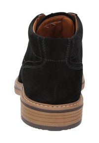 Stivale alla caviglia in suede nero con suola in gomma marrone e cuciture a contrasto. Presenta una punta rotonda e un tacco leggermente sollevato.
