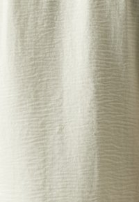 Linen fabric in a light beige color, featuring a textured surface with subtle wrinkling and a soft drape.