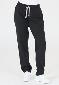 Svarta sweatpants tillverkade av mjukt tyg, med elastisk midja och justerbar dragsko, sidofickor och avsmalnande benslut.