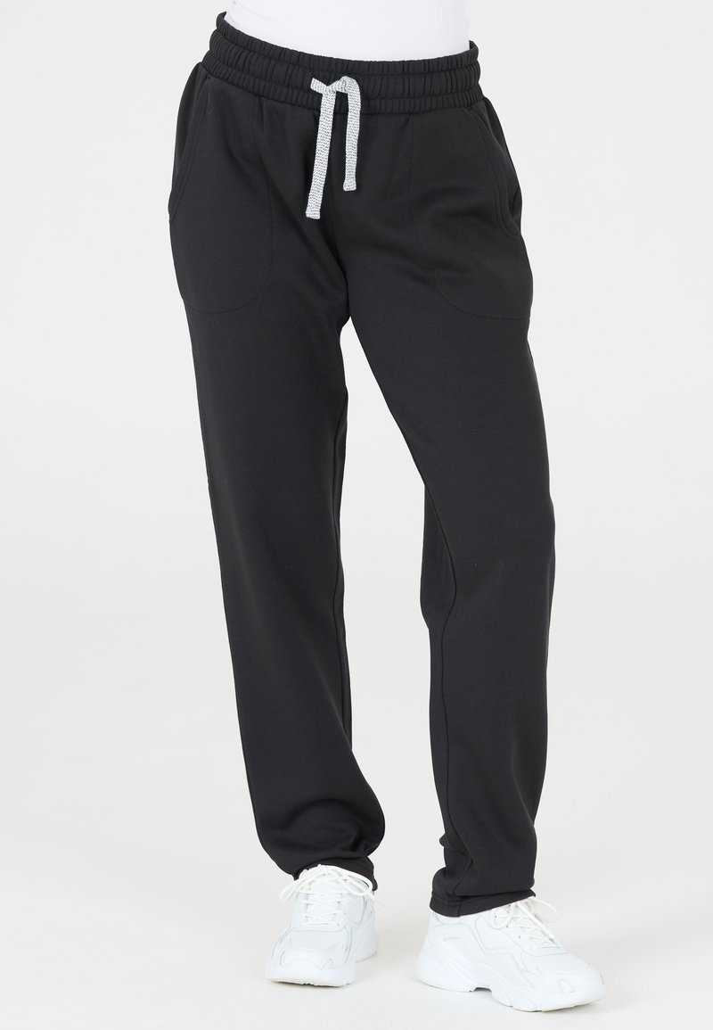 Svarta sweatpants tillverkade av mjukt tyg, med elastisk midja och justerbar dragsko, sidofickor och avsmalnande benslut.