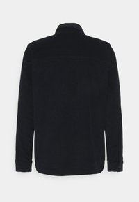 Chaqueta de pana azul oscuro con cuello, mangas largas y puños con botones. Presenta un tejido texturizado y sin cierres visibles en la parte trasera.