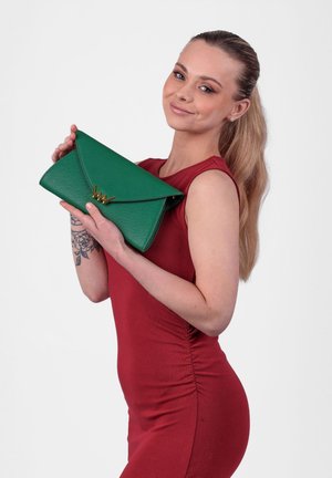 Green textured clutch with a triangular flap and gold hardware. The bag is held against a red dress, highlighting its vibrant color.