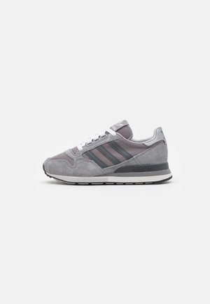 Sneaker Adidas gris et noir avec lacets blancs, matériaux en suède et mesh, design classique à trois bandes et semelle en caoutchouc sur fond blanc.