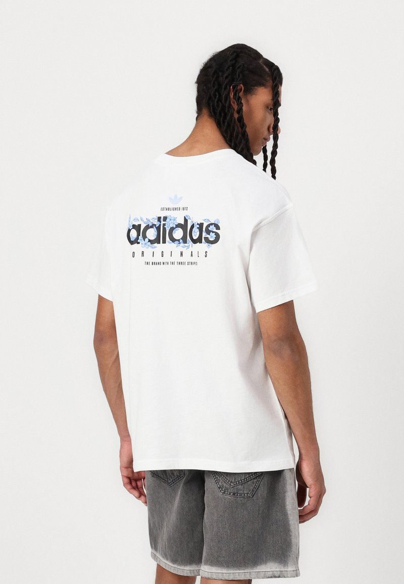 Hvit bomulls t-skjorte med grafisk design i blått og svart med teksten "adidas ORIGINALS", korte ermer og en avslappet passform.
