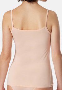Peach-colored tank top with thin straps, fitted design, and smooth texture. No visible patterns or accents on the back.