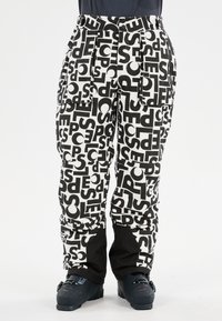 Zwart-witte sneeuwbroek met een gedurfd typografiepatroon, meerdere zakken en zwarte accenten bij de boorden en taille.